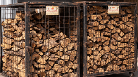 Metal firewood storage cages filled with split hardwood logs used for Texas barbecue smoking